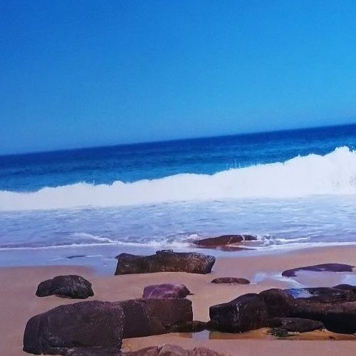 Cette image ouvre une porte vers un espace de paix profonde. Le rivage, parsemé de pierres anciennes, évoque les fondations solides du chemin spirituel : ce qui vous ancre, ce qui vous soutient, ce qui vous rappelle que chaque pas compte. La mer, avec ses vagues douces et régulières, symbolise le mouvement spirituel de la vie : un va-et-vient qui purifie, apaise et renouvelle. Elle porte en elle la mémoire du monde, les bénédictions invisibles, les réponses murmurées par les Forces Divines à celles et ceux qui prennent le temps d’écouter.